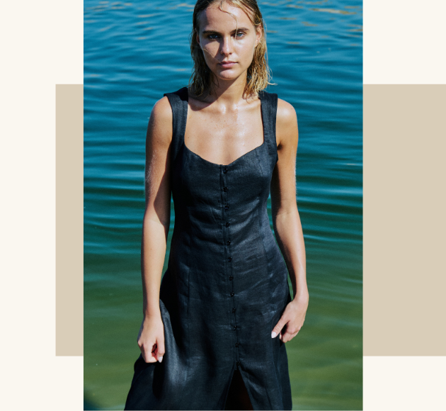 Modella con vestito blu in primo piano, mare sullo sfondo, atmosfera estiva e naturale